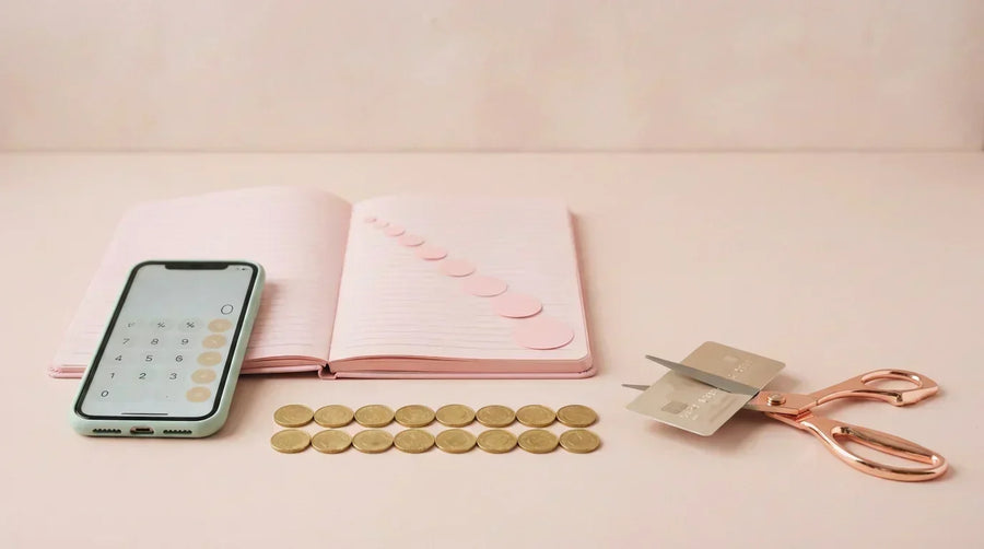 Debt snowball concept with shrinking paper circles, coins and cut credit card on pink background